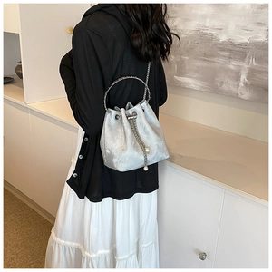 Silver-grey drawstring bucket bag detail with round metal handle and pearl accents