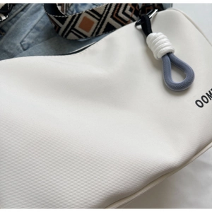 Close-up of white twill fabric shoulder bag with geometric pattern wide strap detail