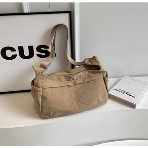 Detail of khaki nylon tote bag showing dual front zippers and wide adjustable strap