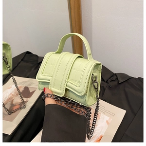 Detail shot of mini light green crocodile embossed handbag with dark metal chain strap