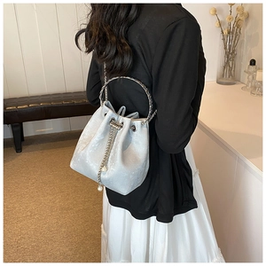 Detail of silver bucket bag featuring pearl-accented chain and metal ring handle