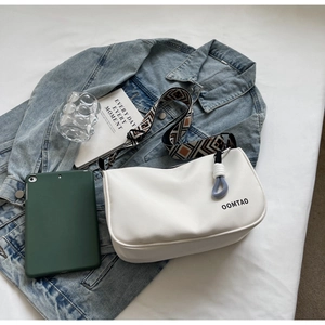Detail of white nylon crossbody bag with jacquard strap on casual bedroom background