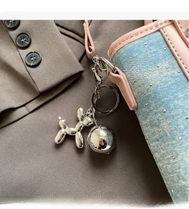 Detail of silver balloon dog keychain with spherical pendant on denim handbag