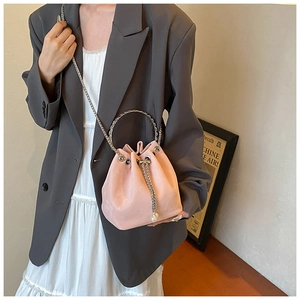 Detail of pink suede bucket bag featuring a silver metal handle and pearl tassel chain