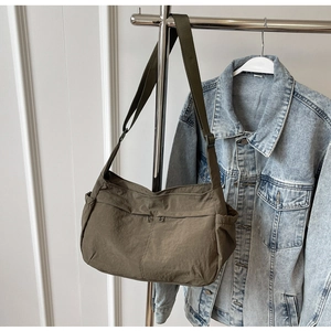 Detail of army green nylon messenger bag with front zippers and adjustable shoulder strap