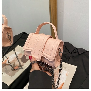 Close-up of pink mini handbag with crocodile pattern texture and metal chain strap