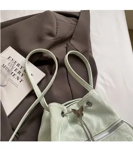 Detail of mint green bucket bag featuring a butterfly charm and drawstring closure