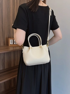 Minimalist beige pebble leather bucket bag with gold hardware and adjustable strap