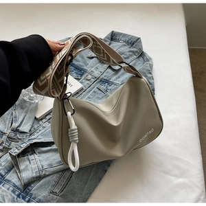 Detail of gray nylon crossbody bag with colorful woven strap on denim jacket