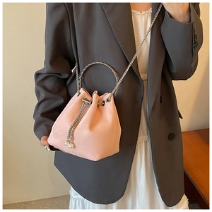 Pink velvet bucket bag with silver ring handle and pearl drawstring tassels on model