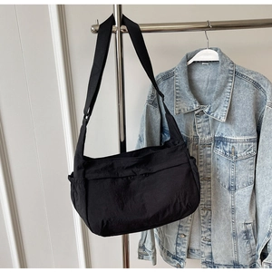Detail view of large black nylon crossbody bag with side pocket and adjustable strap