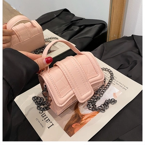 Detail of pink crocodile pattern mini handbag with dark grey metal chain on magazine