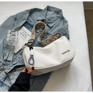 Detailed view of white crossbody bag with ethnic patterned strap and OOMTAO logo lettering
