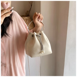 Detail of cream white bucket bag with silver metal handle and elegant pearl charms