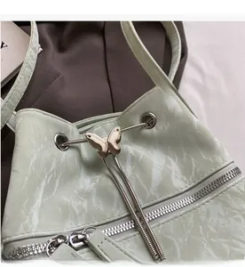 Detail of mint green bucket bag featuring marble texture and gold butterfly drawstring buckle
