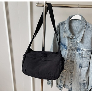 Detail view of black nylon crossbody bag side pocket and adjustable strap on a hanger