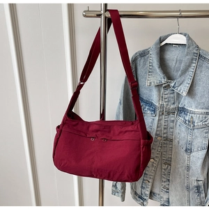 Detail view of burgundy crossbody bag with multiple zip pockets and adjustable wide strap