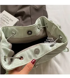 Detail of green bucket bag showing magnetic snap closure and chain drawstring