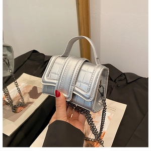 Detail of silver crocodile pattern mini bag with metallic handle and chain strap