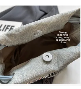 Close-up of silver magnetic buckle on light grey bucket bag with woven texture