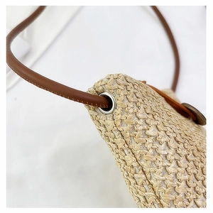 Close-up of woven straw texture with brown leather strap and silver metal eyelet detail