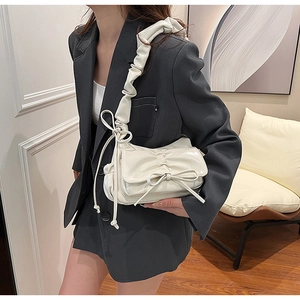 Détail du sac à bandoulière plissé crème avec nœud et finition en cuir verni brillant