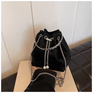 Detail of black velvet bucket bag featuring silver chain and elegant pearl drawstring