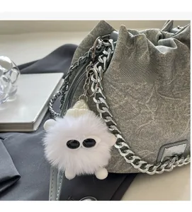 Detail of gray textured bucket bag with chunky silver chain and cute monster plush charm
