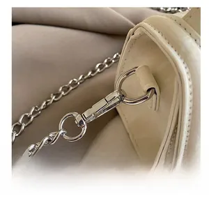 Close-up of premium silver spring hook and metal chain on off-white leather handbag