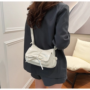 Détail du sac blanc en cuir PU brillant avec grand nœud et plis porté par un mannequin