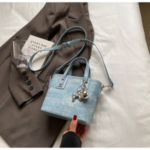Detail of light blue tweed bucket bag with silver balloon dog charm and round handles