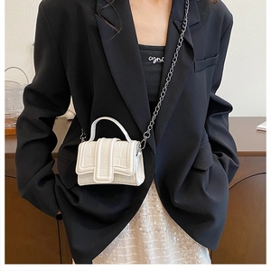 Close-up of white croc-embossed mini handbag with metal chain strap and top handle