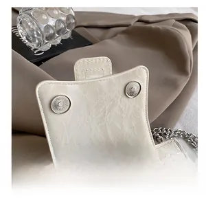 Detail view of the premium off-white handbag with magnetic dual buckles and chain strap