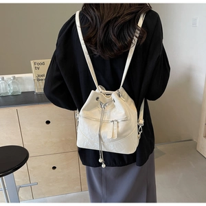 Detail of cream white bucket backpack with butterfly metal buckle and pearl drawstring