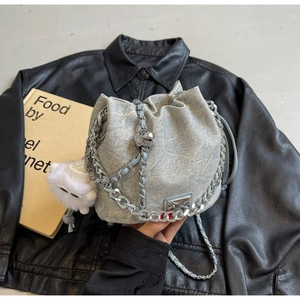 Detail of grey textured bucket bag with silver chain strap and plush ball charm