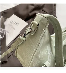 Detail of light green ruched texture and shiny silver metal hardware on shoulder bag
