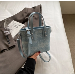 Light blue bucket bag detail with sequins and adjustable strap on neutral background