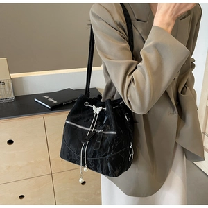 Detail of black pleated bucket bag with silver zipper, pearl fringe and butterfly charm