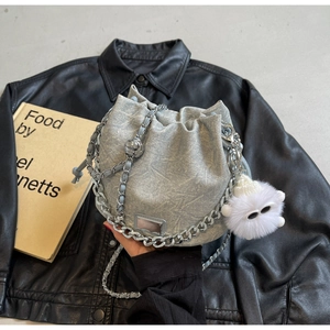 Detail of silver textured bucket bag with metal chain strap and plush monster charm