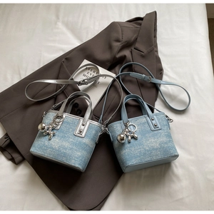 Detail of mini denim crossbody bags with silver balloon dog charms and metal studs