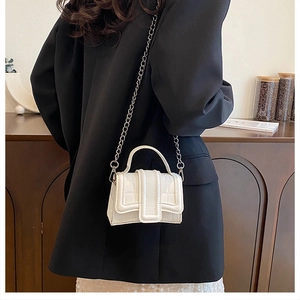 Detailed shot of white croc-embossed mini crossbody bag with silver chain on model