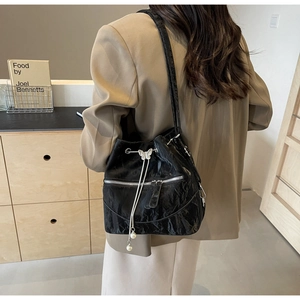 Detail of black pleated bucket bag with silver butterfly hardware and pearl tassel