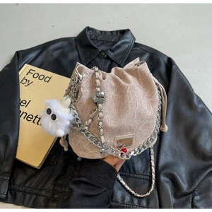 Detail of drawstring bucket bag with chain strap and cute plush monster charm