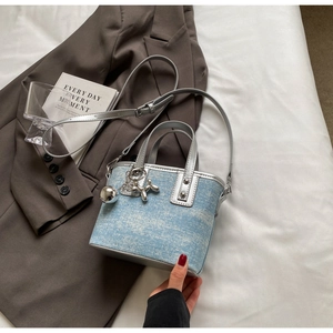 Detail of light blue denim mini bucket bag with silver trim and cute balloon dog charms