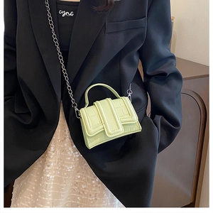 Detail of light green crocodile pattern mini bag with chain strap and handle on model