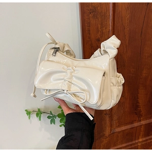 Dettaglio della borsa a spalla plissettata color crema con fiocco e finitura lucida