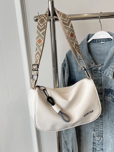 White faux leather crossbody bag with wide geometric pattern strap and charm detail
