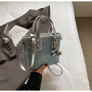 Detail of light blue denim bucket bag with sparkling rhinestones and silver metal hardware