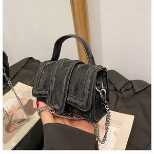 Detail of black textured mini handbag with silver chain strap and top handle