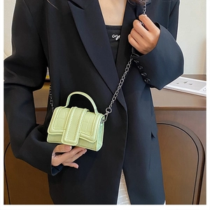 Detail of mint green crocodile embossed mini bag with silver chain strap on model